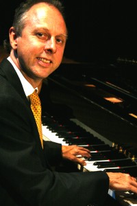 Phil Carrol, piano player, wearing a suit with a yellow tie